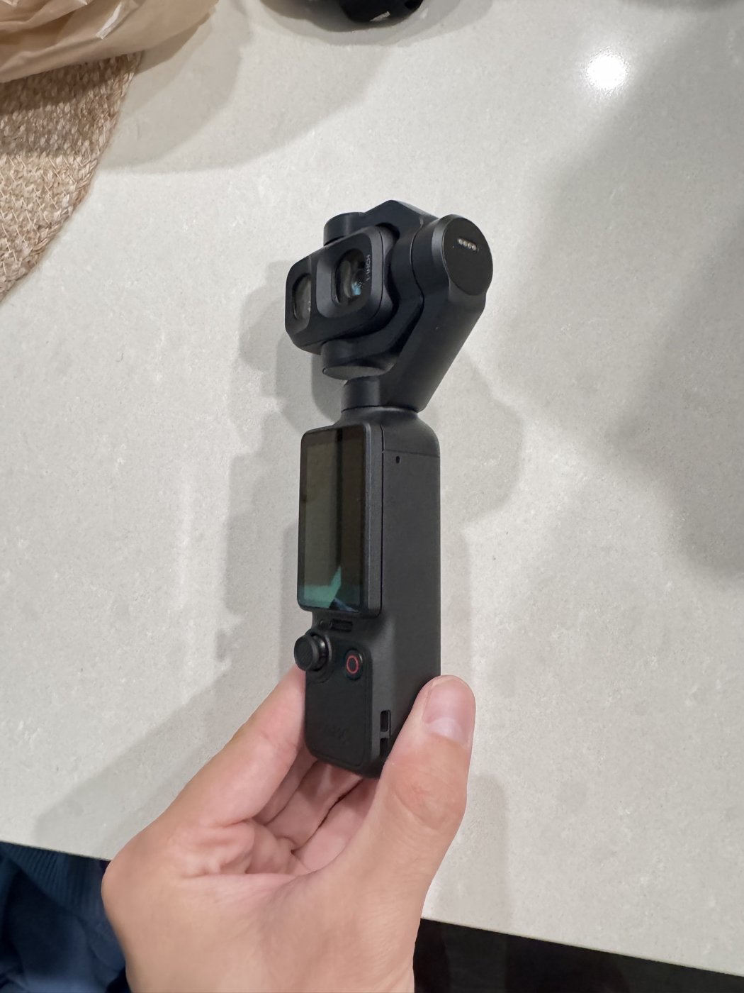 Reference photo of the Osmo Pocket 4P held in hand, screen side