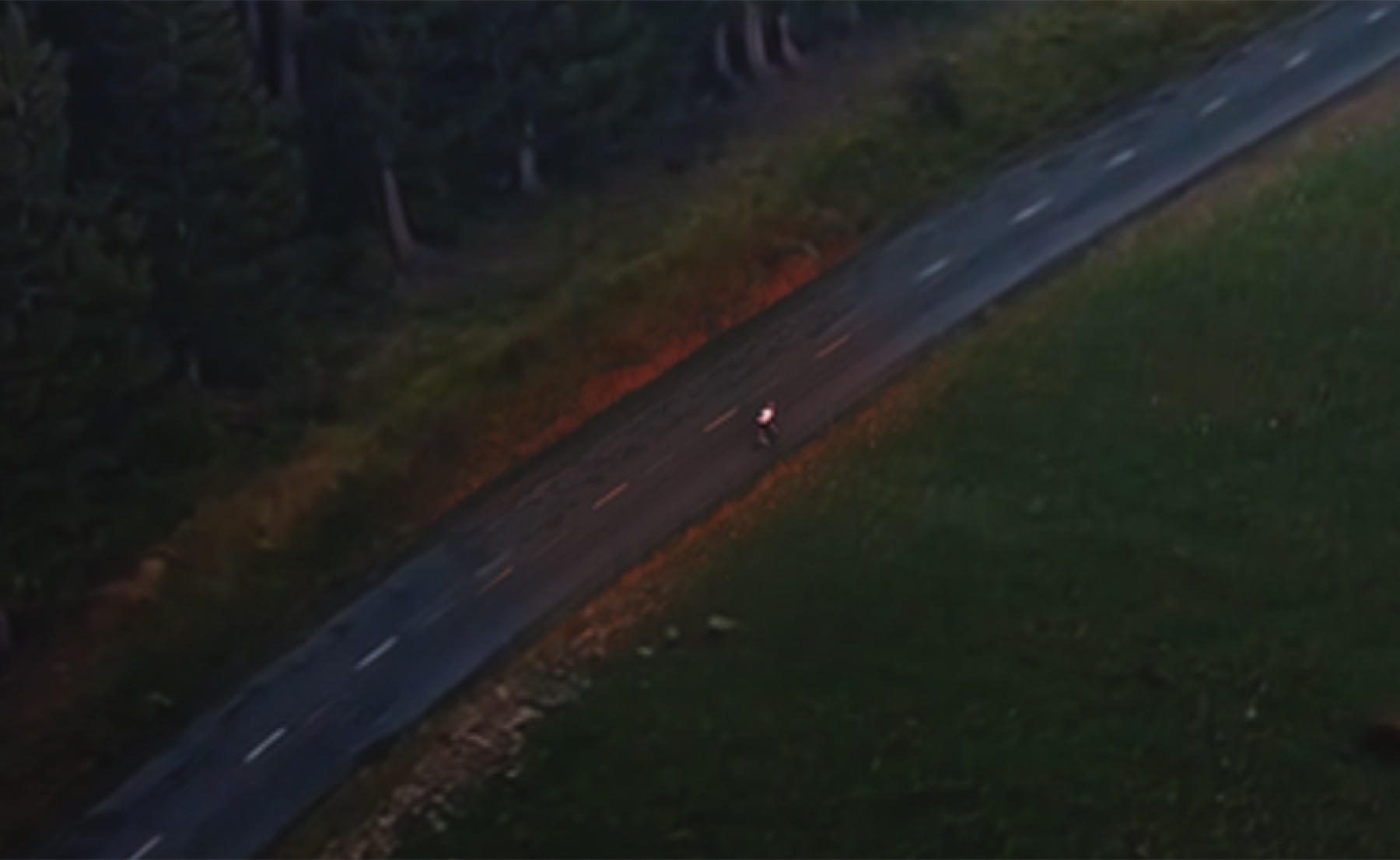 The sunset-colored cyclist patch sitting on top of the cool overcast AI road. The orange warmth reads as obviously out of place.